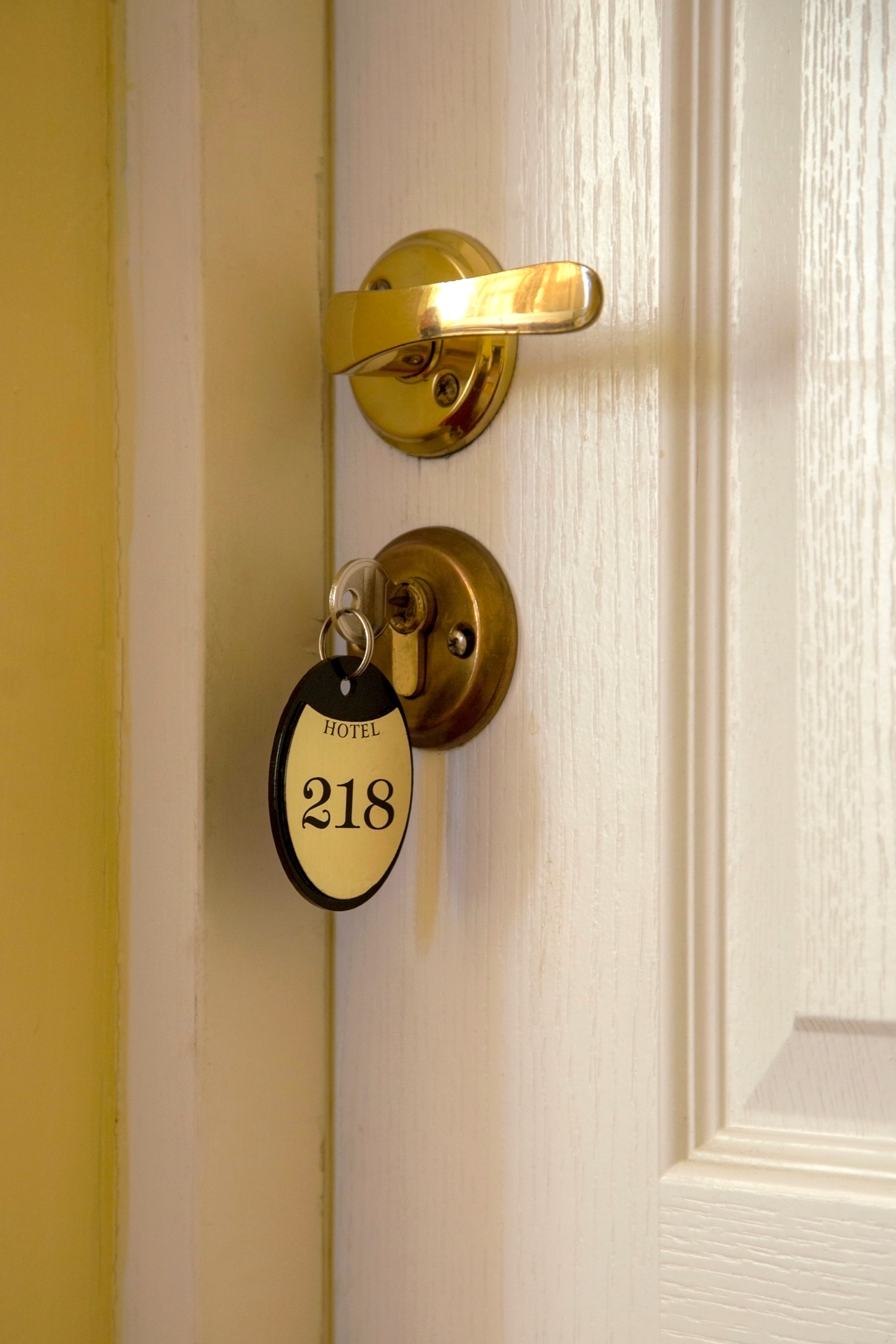 Close-up of a hotel door with brass handle and numbered room key tag