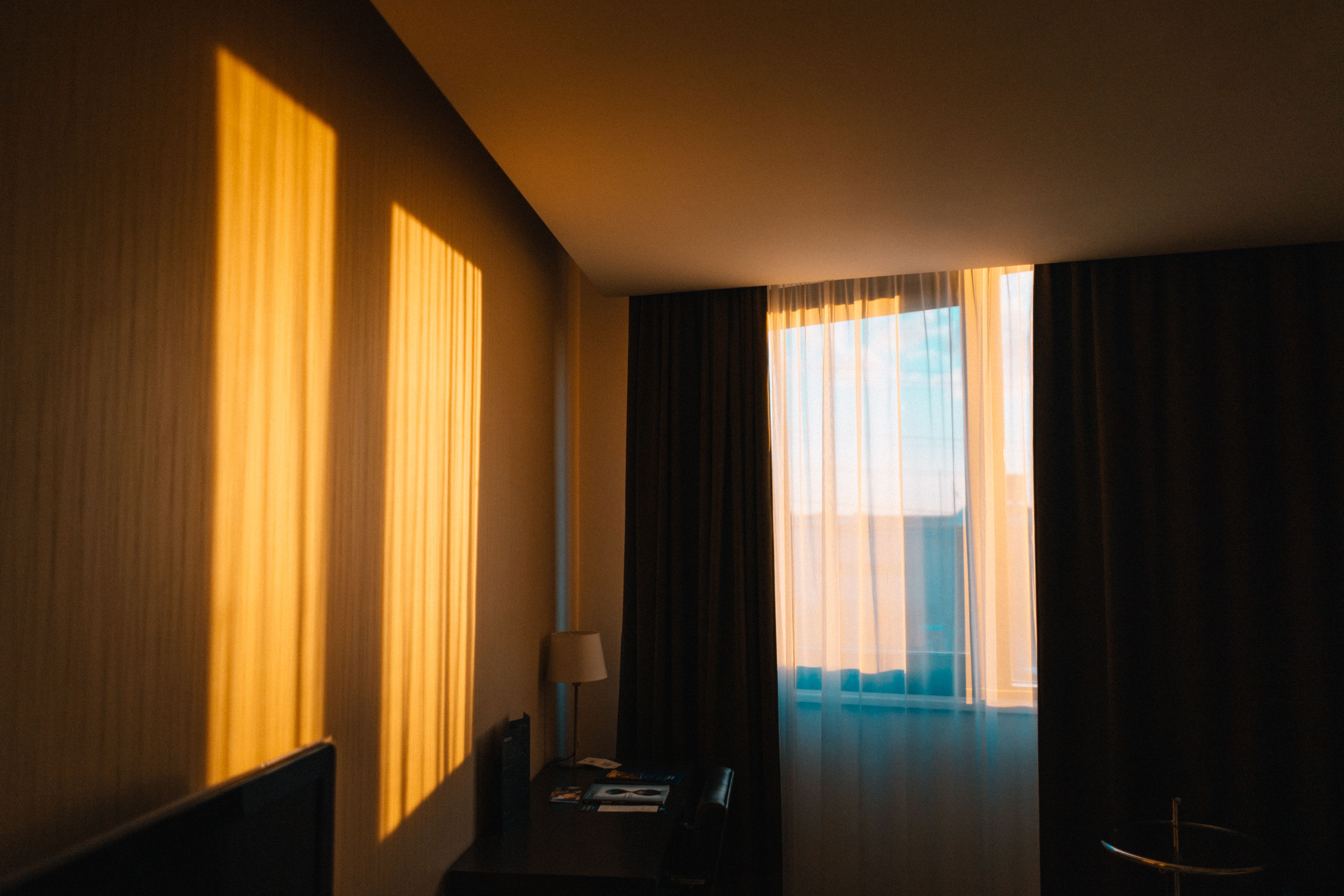 Contemporary hotel room bathed in warm morning light with shadows on the wall