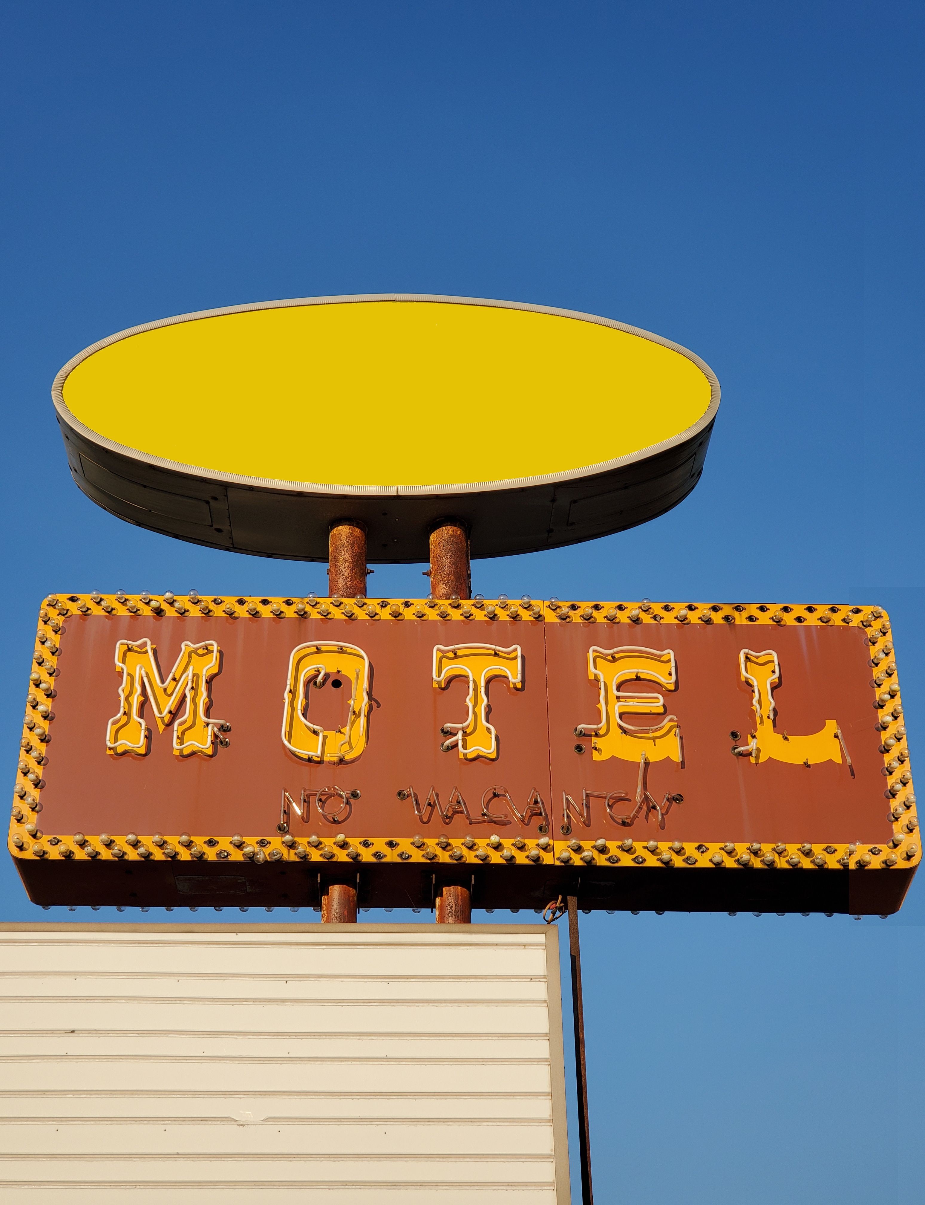 Vintage motel sign reading No Vacancy under a clear blue sky