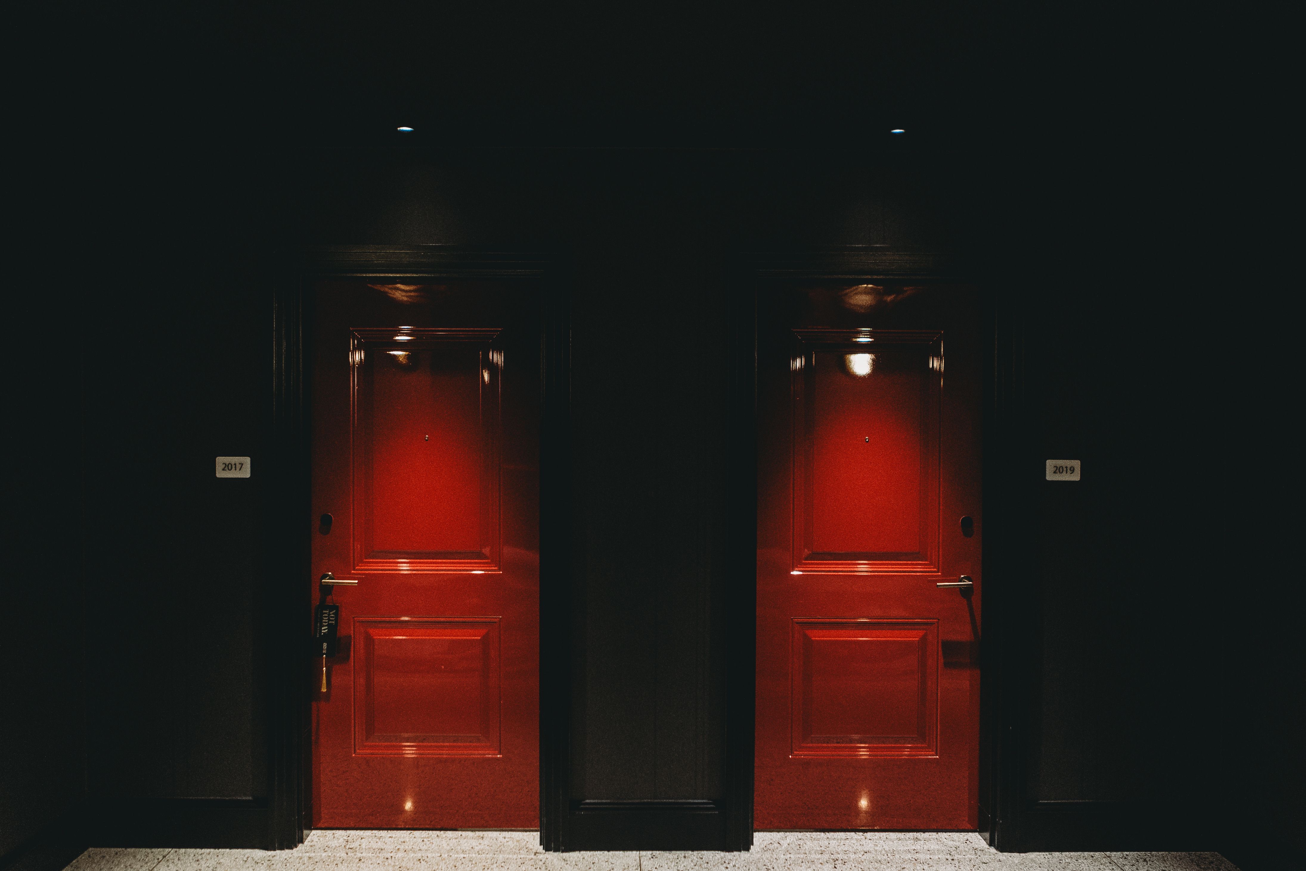 Two illuminated red doors in a dark hotel hallway creating a mysterious ambiance