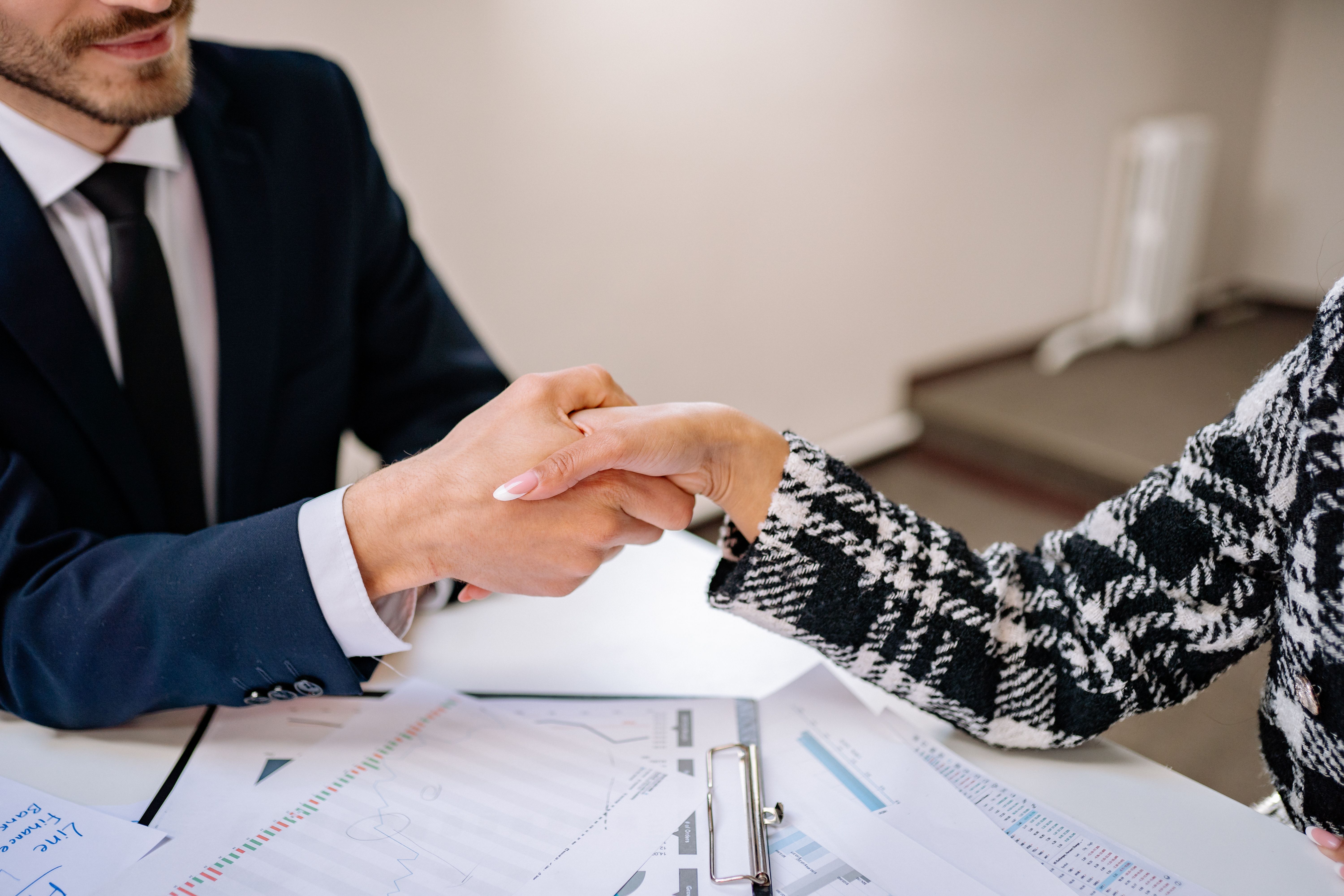 Close-up of a business handshake over documents in an office, symbolizing a client-lawyer agreement