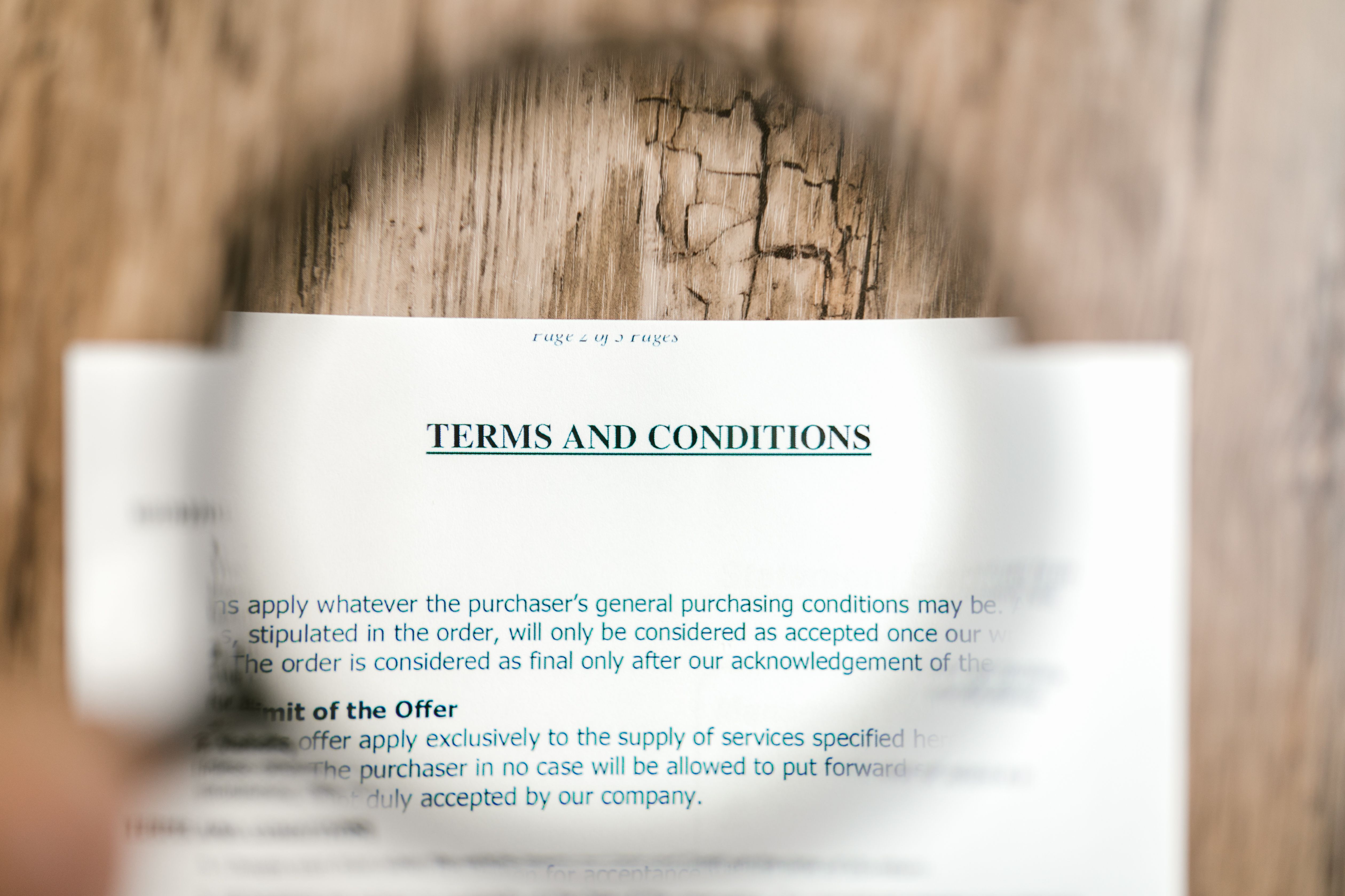 Magnifying glass focusing on terms and conditions fine print in a contract