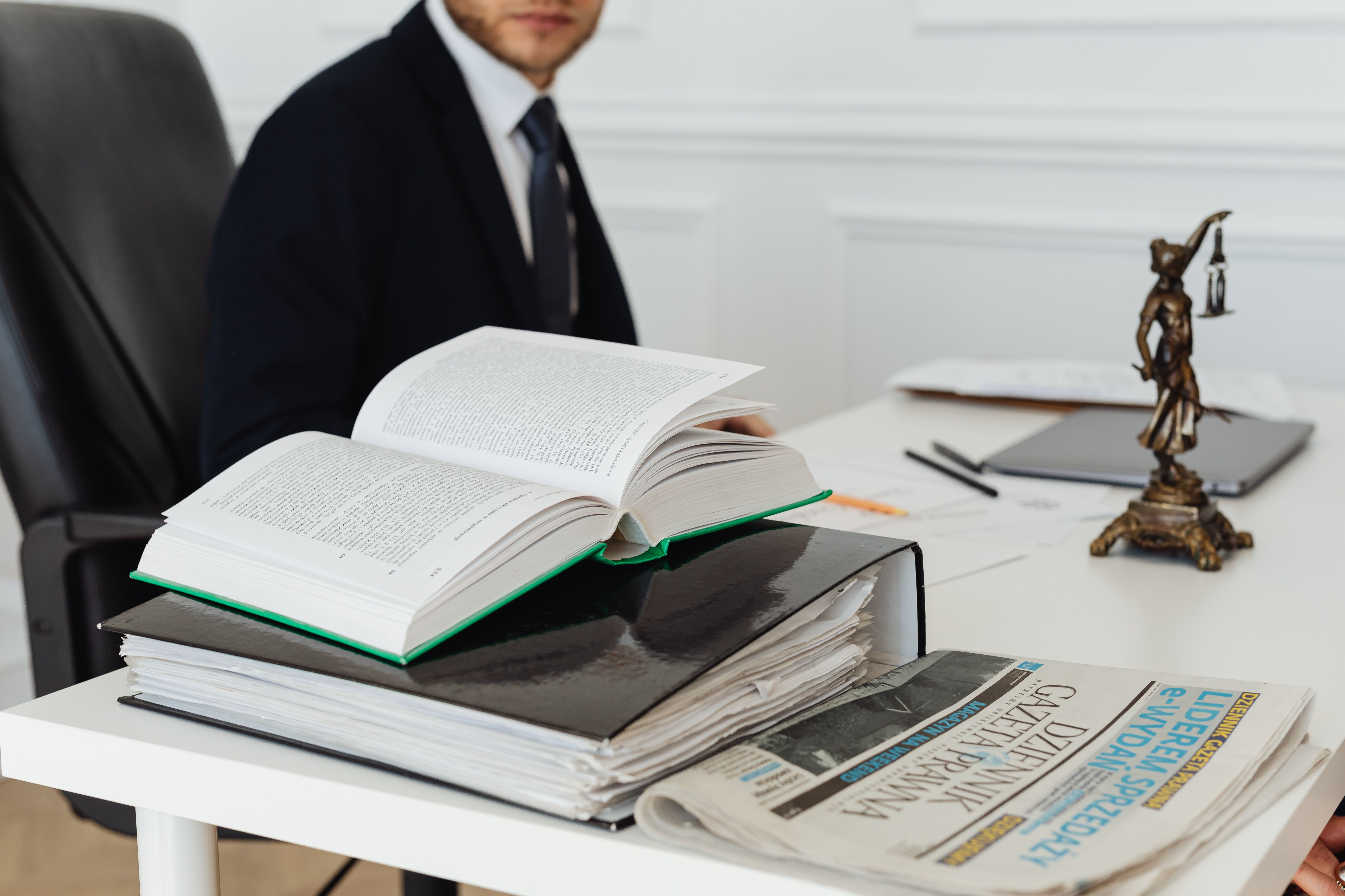 A lawyer sitting at a desk with legal books, documents, and a newspaper, embodying legal professionalism