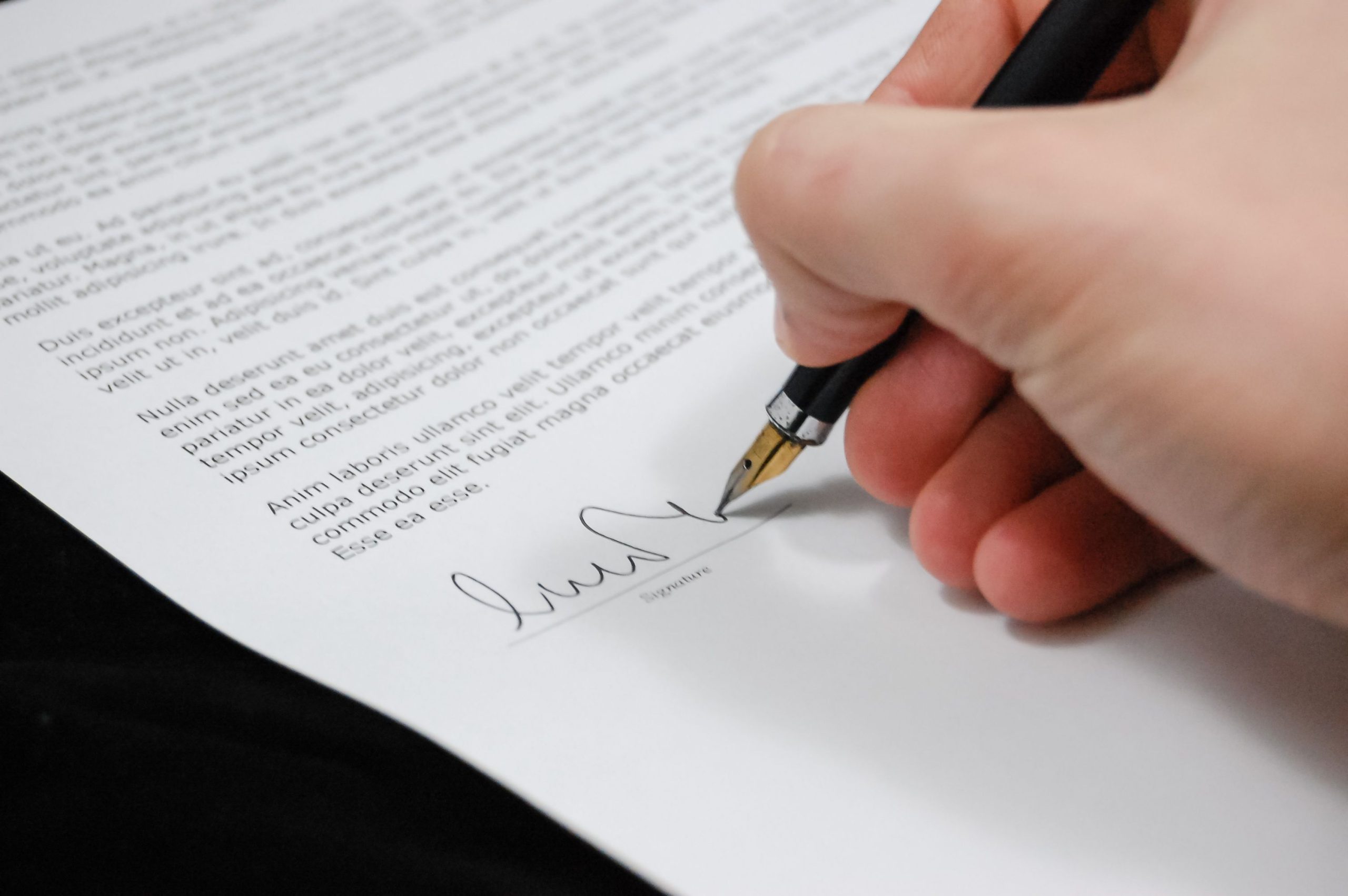 Close-up of a hand signing a legal contract with a fountain pen