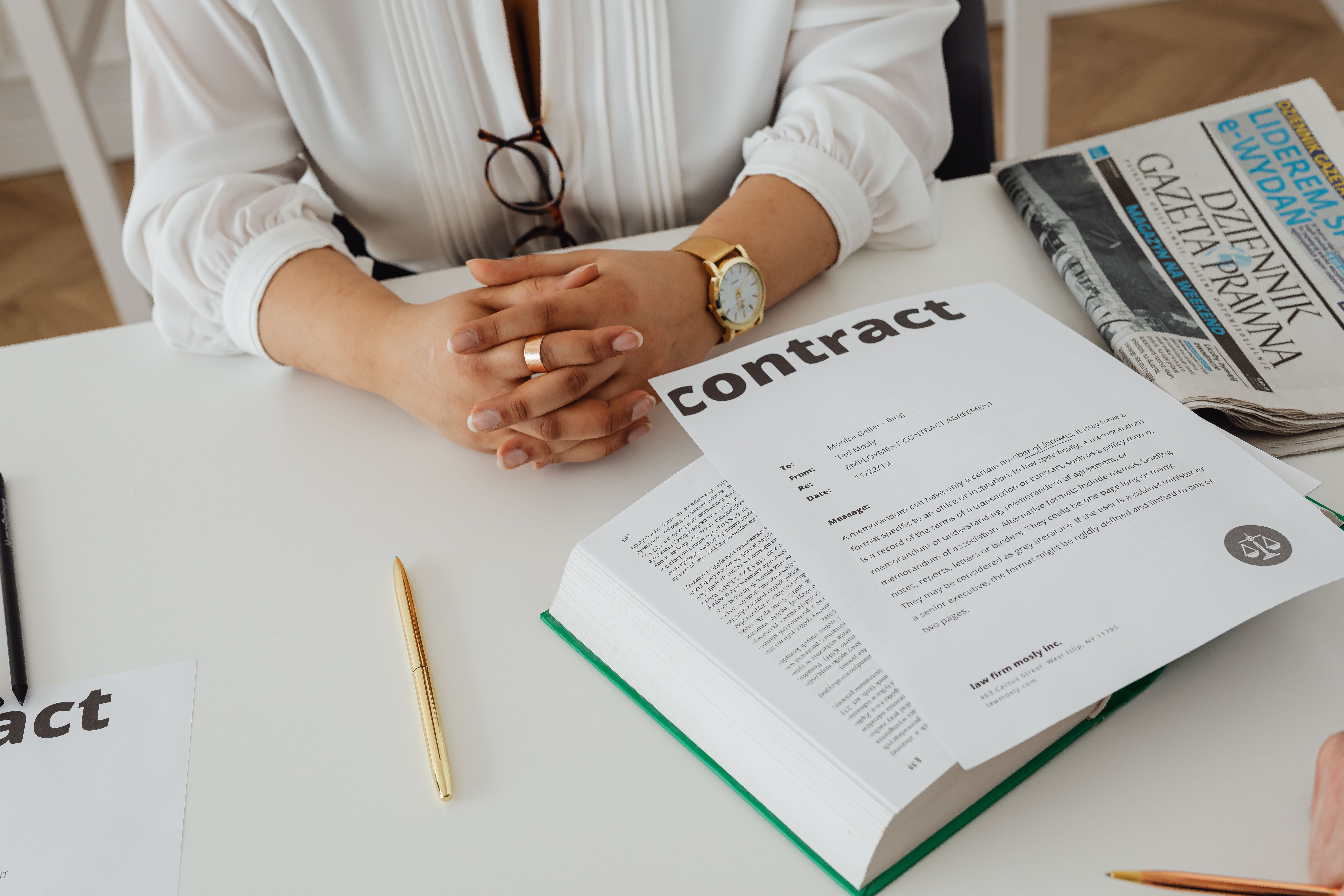 Businesswoman reviewing a contract and legal paperwork at her desk, a practical view of managing creative-industry legal work.